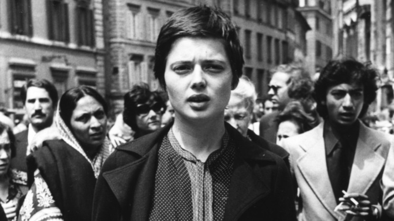 Black-and-white photo of Isabella Rossellini in a crowd of people with a neutral expression in 1977