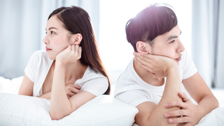 Couple sitting on bed fighting