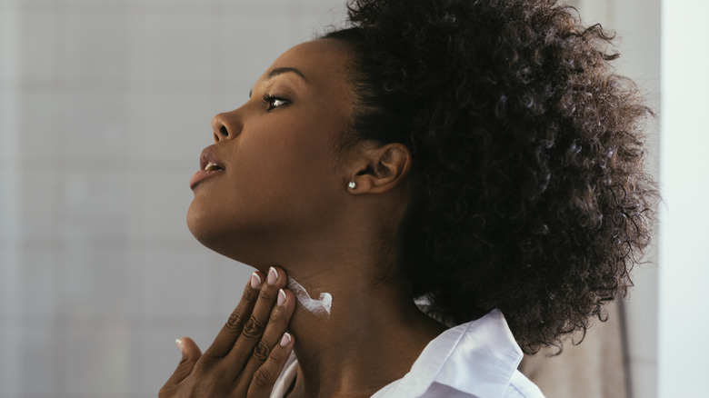 woman rubbing lotion on neck