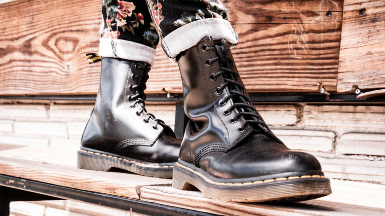 Person in combat boots standing on a wooden plank