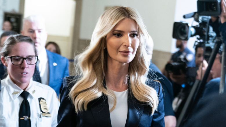 Ivanka Trump walking through a room with cameras and people