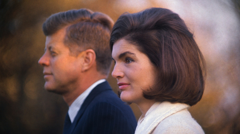 Jackie Kennedy in profile with John F Kennedy in the background