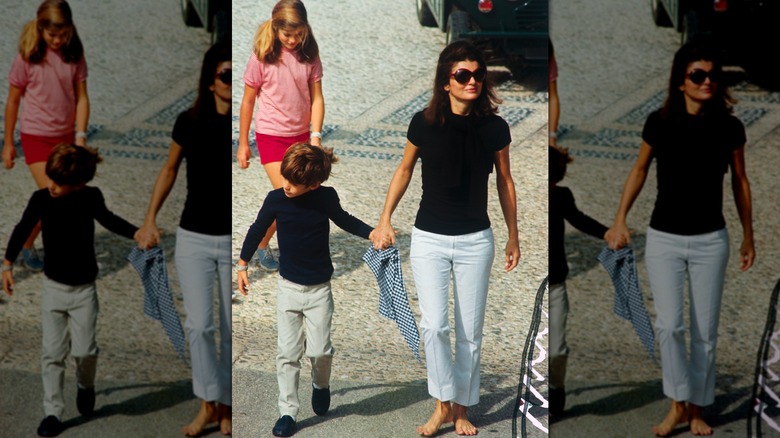 Jackie Kennedy in white pants and a black shirt with her children