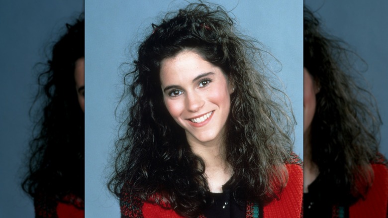 Jami Gertz smiling in a photo shoot from around 1985 with long, potentially permed, hair