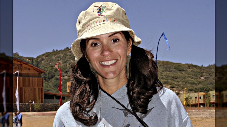 Jami Gertz smiling with her hair in pigtails while wearing a bucket hat in 2004