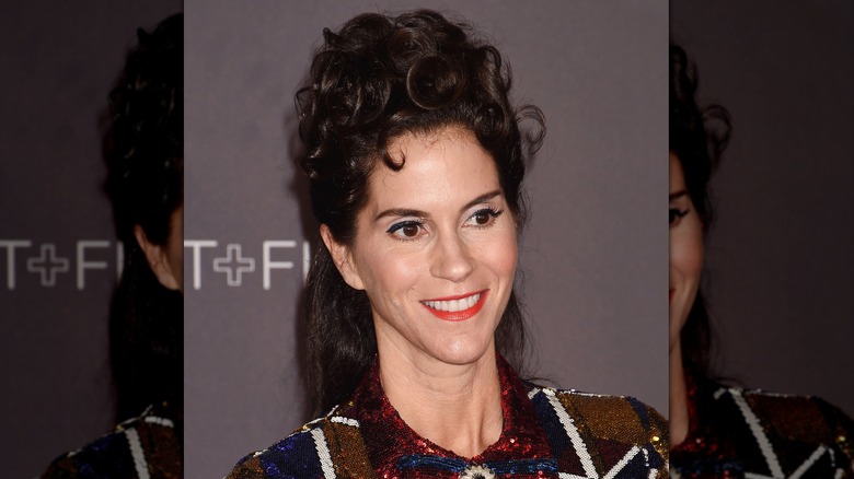 Jami Gertz posing with a curly, half up, half down hairstyle on the red carpet in 2017