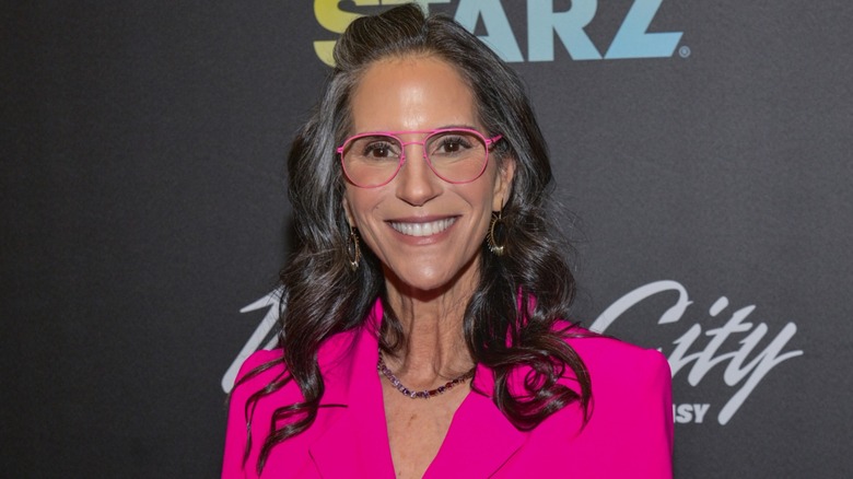 Jami Gertz smiling on the red carpet in 2025 while showing her wavy gray hair