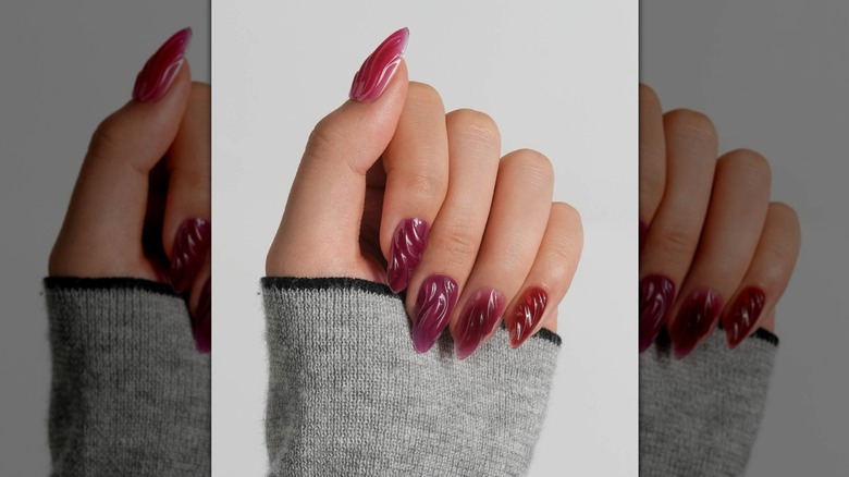 Closed hand showing a berry-colored manicure with a 3D texture