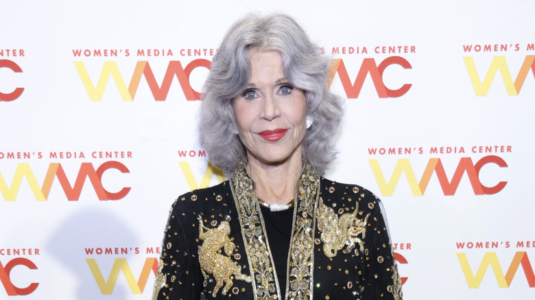 Jane Fonda at an event with gray hair and a black and gold jacket