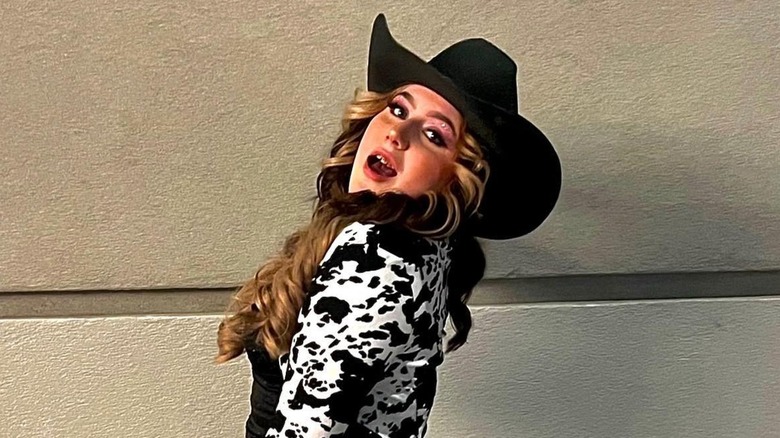 Bailee Ann DeFord posing in a black cowboy hat and a cow print jacket in 2026