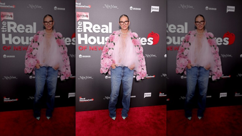 Jenna Lyons poses wearing an oversized pink floral jacket and denim jeans
