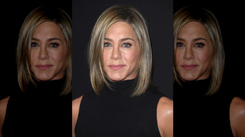 Jennifer Aniston posing with a small smile while wearing her hair in a shoulder-length lob