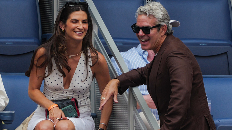 Kaitlan Collins speaking with Andy Cohen at the US Open, with her polka-dotted top visible without her bomber jacket