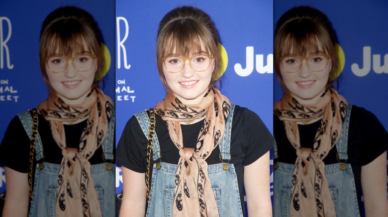 Kaitlyn Dever wearing a pulled-backed hairstyle with bangs across her forehead at a Just Jared event