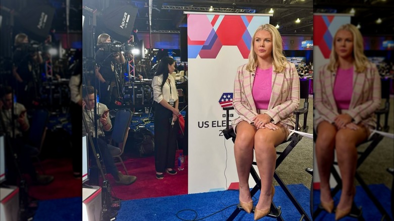 Karoline Leavitt seated in a beige and pink skirt suit.