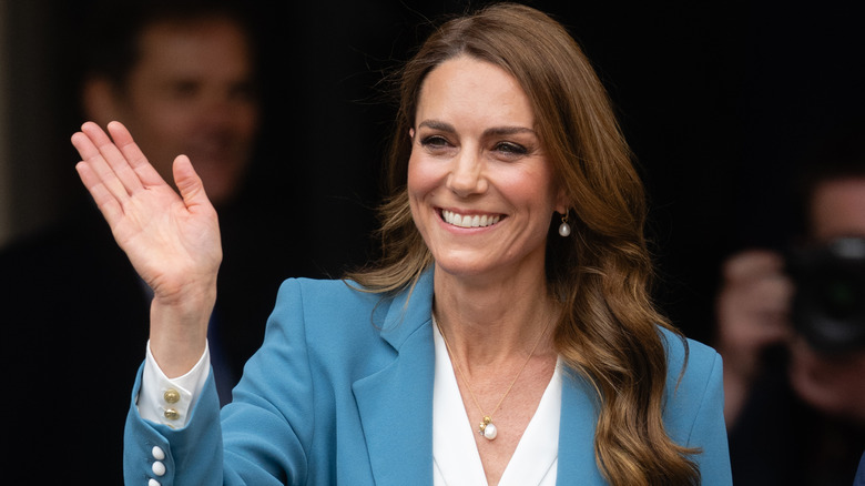 Kate Middleton smiling and while waving and wearing a blue blazer and white top