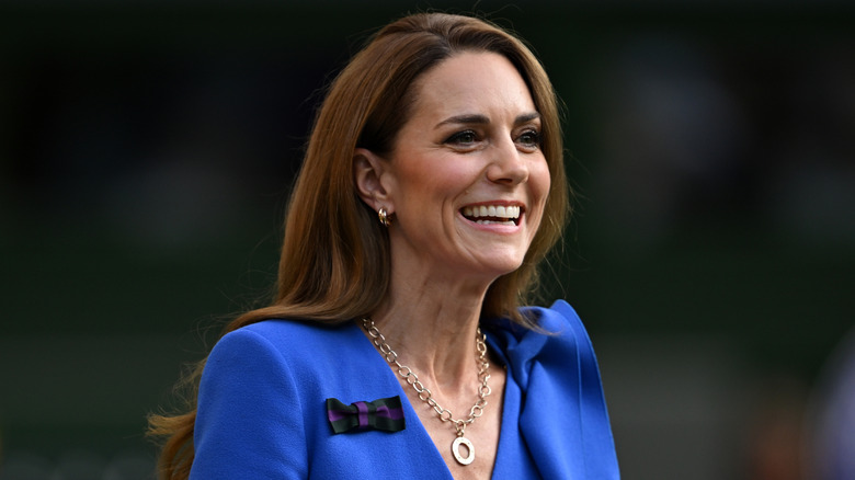 Kate Middleton smiling in a blue dress looking away from the camera