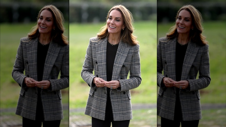 Kate Middleton standing in a field wearing a plaid blazer