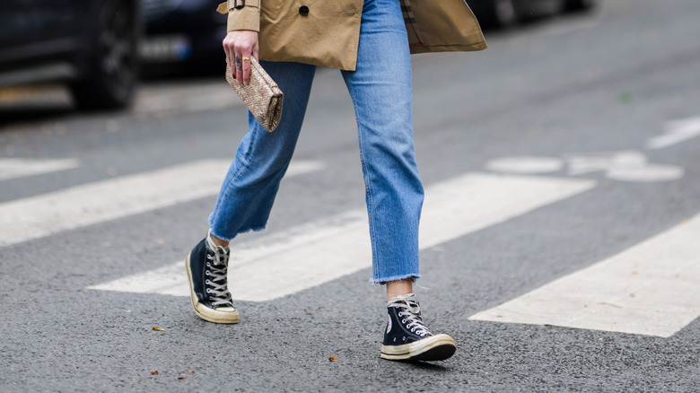 Close-up of cropped jeans worn with Converse sneakers
