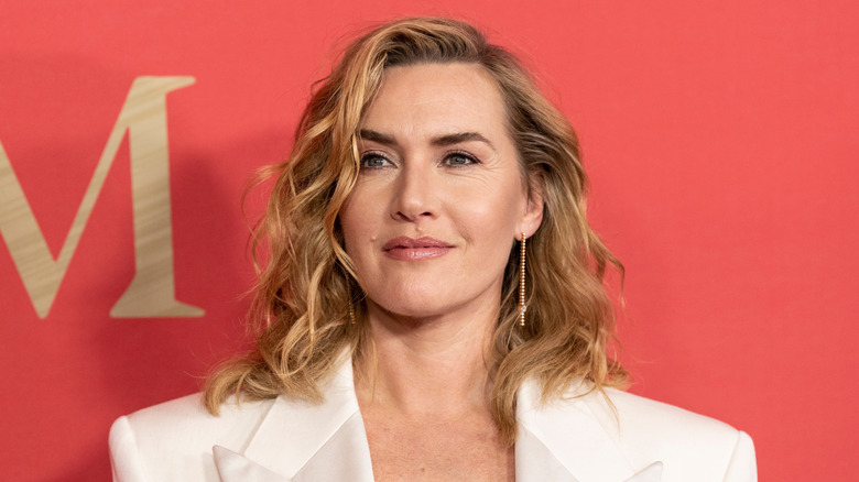 Kate Winslet smiles wearing a white blazer