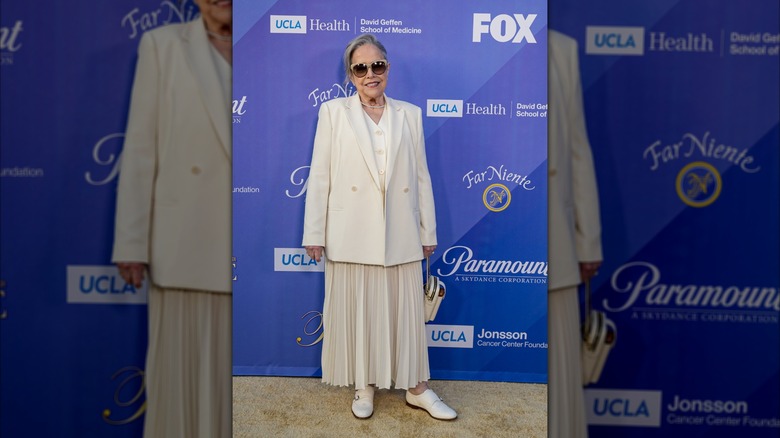 Kathy Bates wearing an all white suit and beige sunglasses