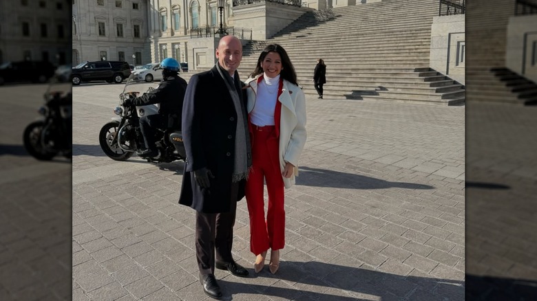 Stephen Miller smiling next to Katie Miller while posing outside