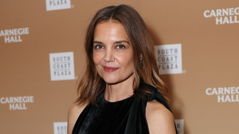 A close-up of Katie Holmes wearing black in front of a step and repeat