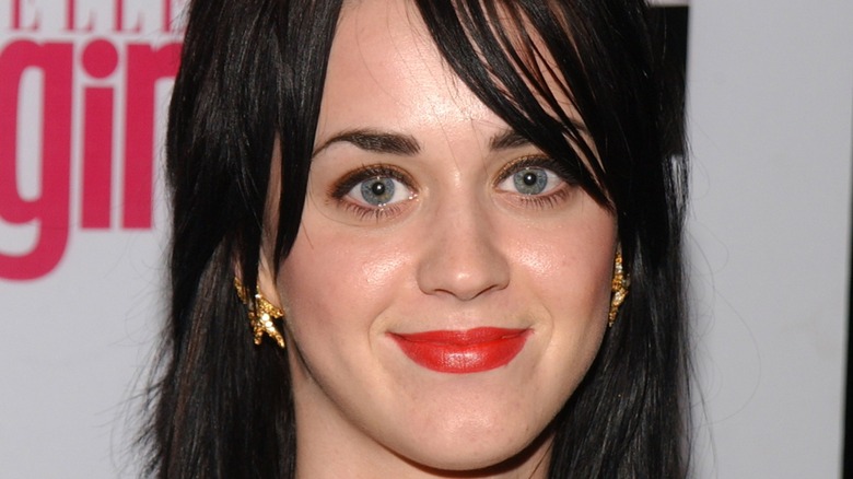 Katy Perry smiling on the red carpet wearing red lipstick in 2004