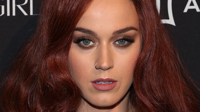 Katy Perry with a sultry expression at the 2015 Harper ICONS Party with dark red hair