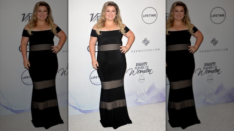 Kelly CLarkson on the red carpet in a black dress with horizontal stripes