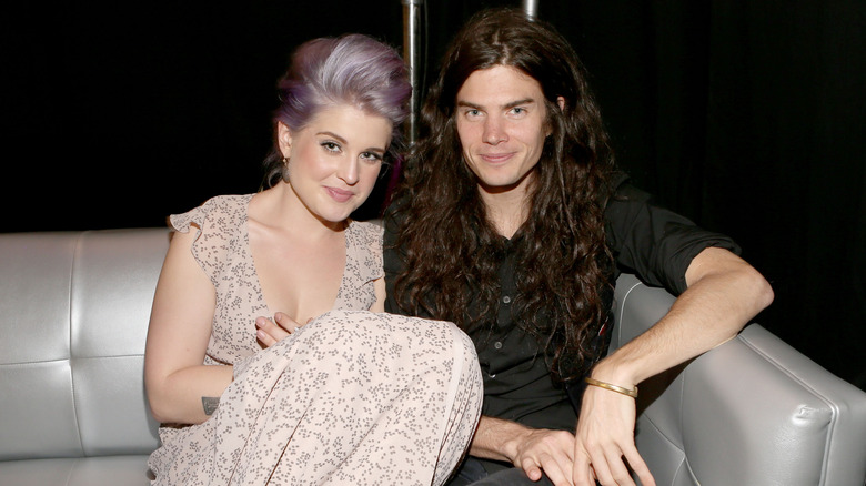 Kelly Osbourne on a silver couch sitting next to Matthew Mosshart at the 2012 Do Something Awards