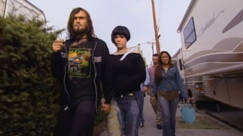 Bert McCracken holding hands with Kelly Osbourne as they walk on the sidewalk with a group of people