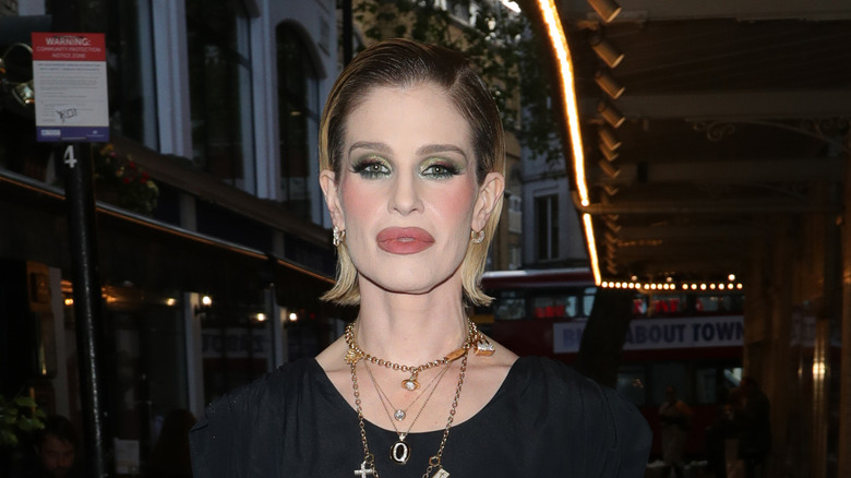 Kelly Osbourne in gold necklaces and a black top walking outside