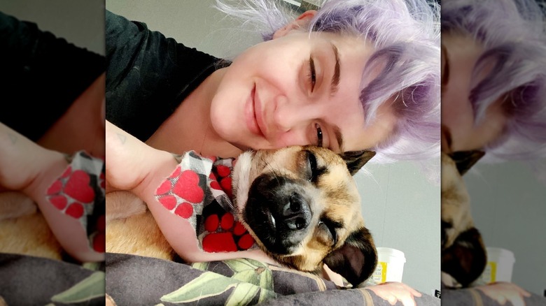 Kelly Osbourne posing cheek-to-cheek with a dog wearing a bandana