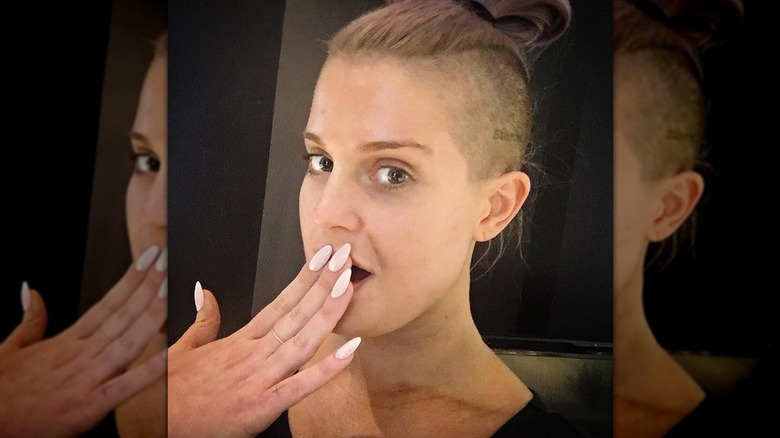 Kelly Osbourne posing for a selfie while putting a manicured hand over her open-mouth