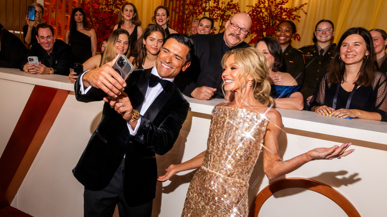Mark Consuelos and Kelly Ripa posing with onlookers at the 2026 Oscars