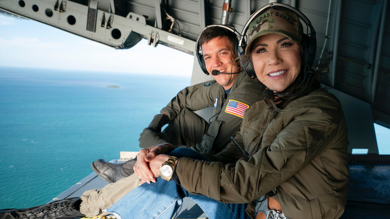 Kristi Noem seated in the open rear cargo door of a U.S. Coast Guard C-130