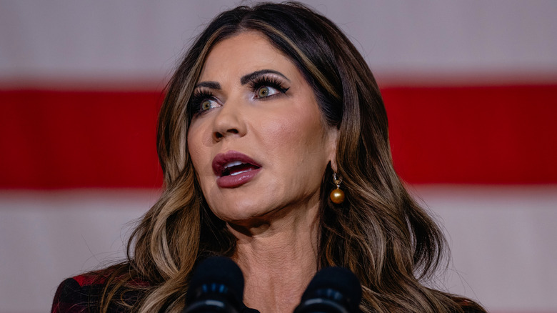 Kristi Noem speaking to a crowd with golden pearl earrings