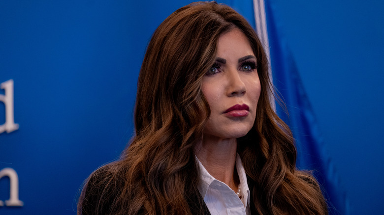 Kristi Noem in a white shirt with pearls and a dark blazer at an event