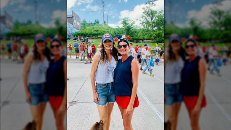 Kristi Noem on a street wearing cutoffs next to a woman in Fourth of July clothes