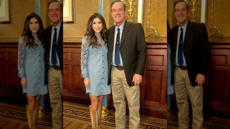 Kristi Noem in a chambray shirt dress, standing next to a man in khakis and a sport coat