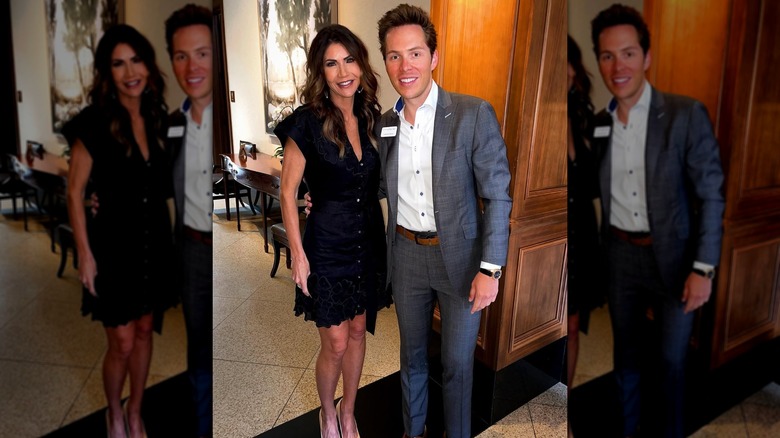 Kristi Noem wearing a black dress and standing next to a young man in a suit