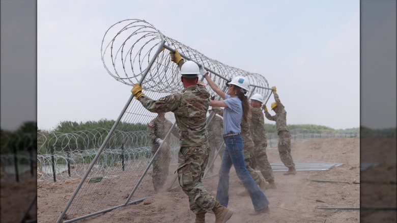 Kristi Noem putting up a fence with barbed wire on top