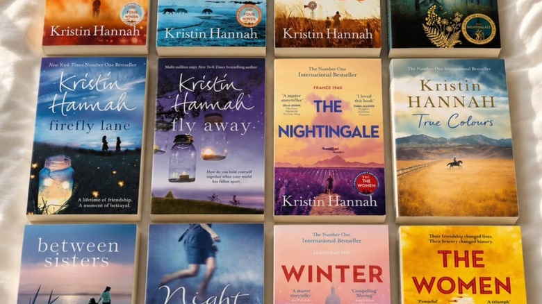 A collection of Kristin Hannah books laid out on a bed