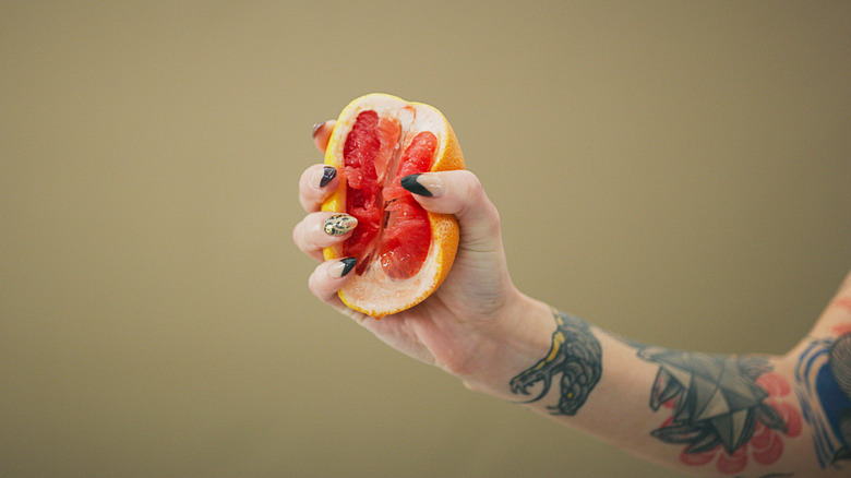 A person squeezing a grapefruit