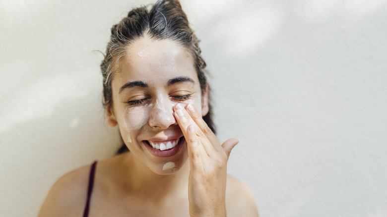 Woman smiling and applying skincare