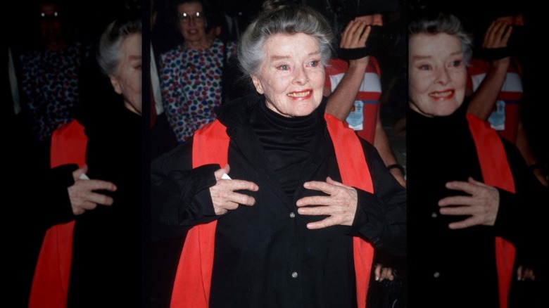 Katharine Hepburn similing at an event in New York City wearing black and red