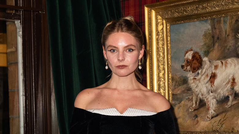 Nell Hudson posing in front of a painting of a spaniel