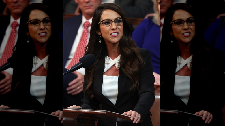 Lauren Boebert at a podium wearing a cutout white top and black jacket