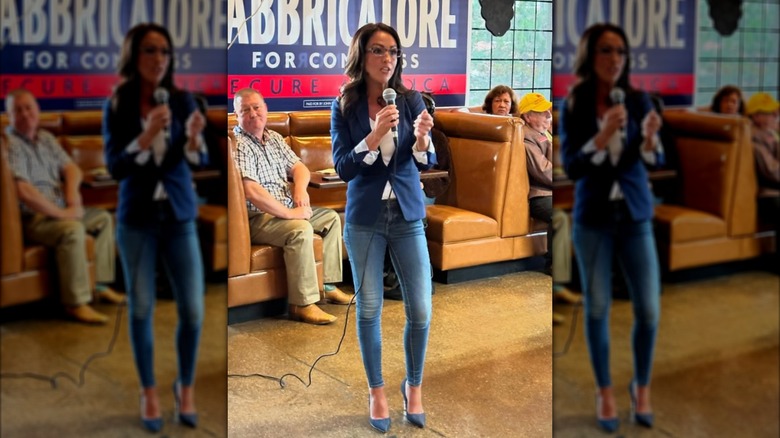 Lauren Boebert standing at a campaign event in skinny jeans and a blue blazer